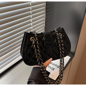Close-up of black quilted shoulder bag with gold chain and refined leather texture
