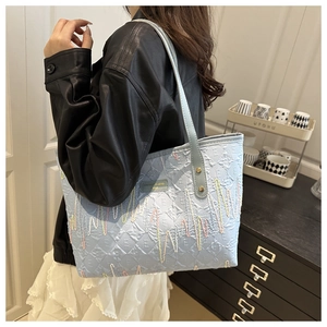 Detailed view of light blue textured tote bag with multi-colored zigzag embroidery