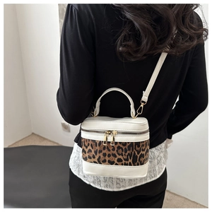 Detail shot of leopard print cylinder bucket bag featuring white trim and gold zippers