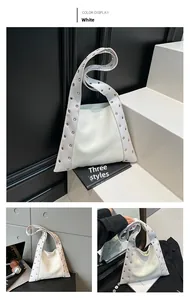 Détail du sac hobo blanc clouté avec œillets en métal doré et forme trapèze minimaliste