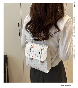 Détail d'un mini sac à dos blanc en cuir avec motifs de petits chiens et cerises