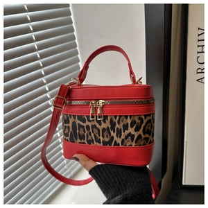 Detail of red leather vanity bag with leopard print panel and gold dual zippers