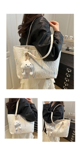 Close-up of white quilted tote bag with colorful embroidery and plush cloud charm