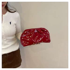 Détail d'une pochette plissée en cuir rouge avec rivets dorés polis et forme de nuage