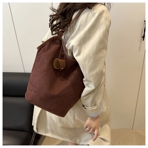 Detail of dark brown faux suede tote bag featuring a minimalist bucket shape and strap