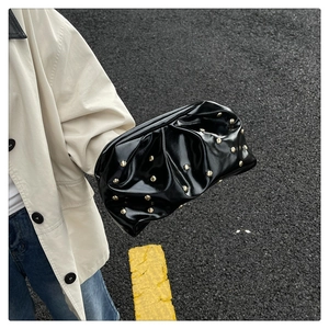 Photo de rue d'un sac nuage plissé noir avec des clous dorés et finition brillante