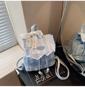 Detail of blue plaid canvas backpack with white lace bow and drawstrings