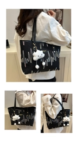 Detail of black embroidered tote bag with wavy patterns and plush cloud charm accessory