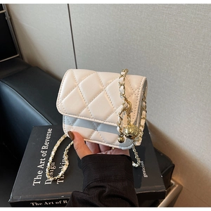 Détail du mini sac blanc matelassé avec bandoulière chaîne dorée et boule décorative