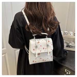 Détail du mini sac à dos blanc avec imprimés chiots et cerises porté par un mannequin