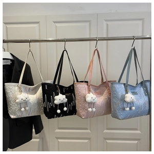 Dettaglio di quattro borse tote trapuntate in bianco nero rosa blu con ciondoli a nuvola
