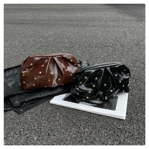 Détail de pochettes nuages tendance en marron chocolat et noir avec rivets dorés