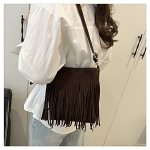 Detailed view of dark brown faux suede crossbody bag featuring dense retro fringe tassels