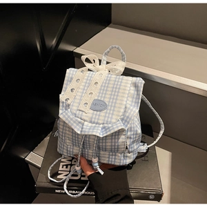 Detail of blue plaid canvas backpack featuring white lace bow and drawstring with beads