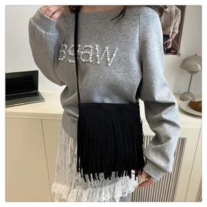 Detail of black bohemian tassel crossbody bag with dense fringe on faux suede fabric