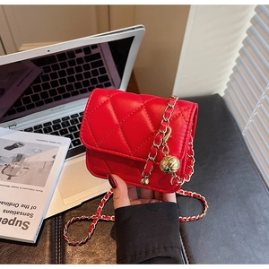Détail d'un petit sac bandoulière rouge matelassé avec chaîne dorée et pendentif