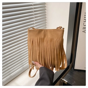 Detail of bohemian tan suede crossbody bag featuring long fringe and vintage texture