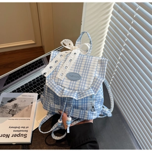 Detail showing blue gingham pattern, lace bow, and decorative ruffle edge on the canvas backpack