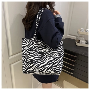 Detail view of a large zebra print canvas tote bag with shoulder strap for daily commuting
