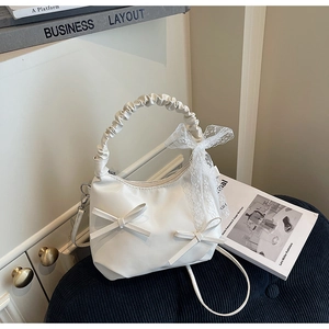 Détail du sac en cuir mat blanc avec rubans de dentelle et nœuds décoratifs