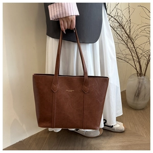 Detailed view of brown vintage leather tote bag with embossed text and dual handles