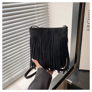 Detailed close-up of a black fringe crossbody bag with long suede tassels and slim strap