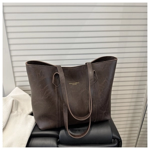 Close-up of deep brown tote bag featuring fine leather texture and golden lettering