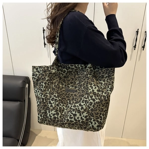 Detail view of large leopard print canvas tote bag with fashion label and front pocket
