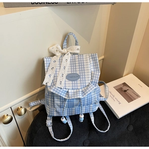 Close-up of blue plaid canvas backpack featuring lace bow and ruffle edge detail