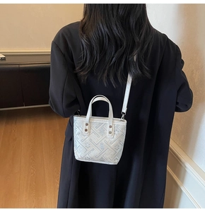 Detailed back view of a white mini bucket bag with geometric embroidery on a crossbody strap