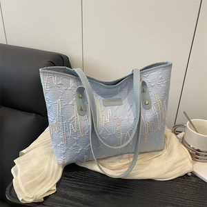 Light blue faux leather tote bag with diamond quilting and colorful wavy embroidery detail
