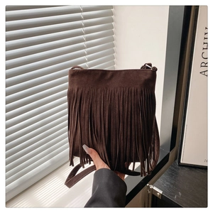 Detailed close-up of dark brown suede crossbody bag featuring long vintage style tassels