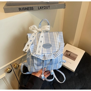 Detailed view of light blue checkered canvas backpack with lace bow and drawstring close
