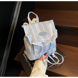 Detail of drawstring closure and ruffled edges on a blue gingham canvas backpack