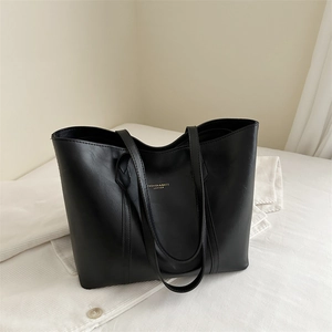 Large capacity black leather tote bag with gold lettering shown on a textured fabric