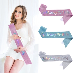 Close-up of glittery Mommy To Be sashes in pink, blue and silver with laser foil text