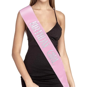 Detail of pink satin Birthday Girl sash with silver lettering worn on a black dress