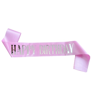 Close-up of pink satin birthday sash featuring metallic silver Happy Birthday lettering