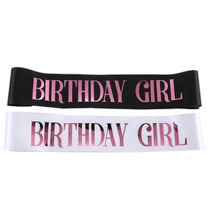 Detail of black and white Birthday Girl satin sashes with glittery purple lettering