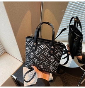 Detail of black embroidered bucket bag with geometric floral patterns and dual handles