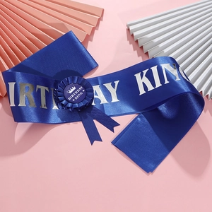 Détail de l'écharpe et du badge Birthday King bleu roi sur un fond rose élégant