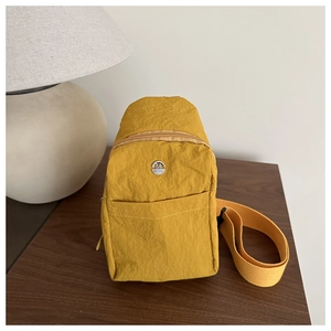 Detail of yellow wrinkled nylon chest bag featuring M FASHION metal logo and zipper pocket