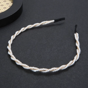 Eleganter Perlenhaarreif mit goldfarbenem Metalldrahtgeflecht auf dunklem Hintergrund