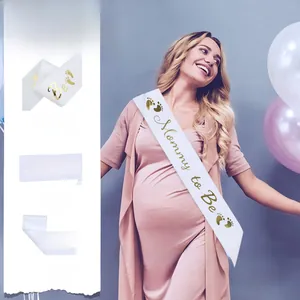 Close-up of white Mommy to Be sash featuring elegant gold foil lettering and baby footprints