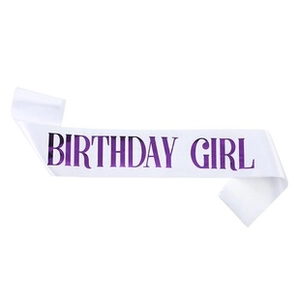 Macro detail of white satin Birthday Girl sash with metallic purple foil lettering