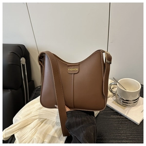 Minimalist brown crescent hobo bag with gold fashion tag in a lifestyle setting