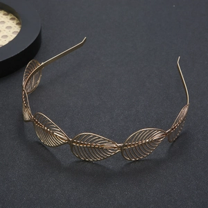Detailed view of golden leaf bridal headband on a minimalist dark textured background