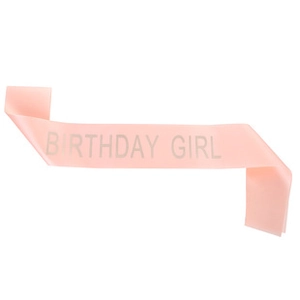 Close-up of pink satin Birthday Girl sash with shimmering silver glitter text detail