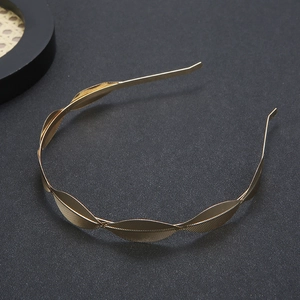 Macro detail of golden metal leaf headband featuring textured alloy leaf patterns