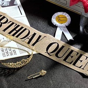Close-up of birthday party set with gold glitter sash, rhinestone crown, and satin badge
